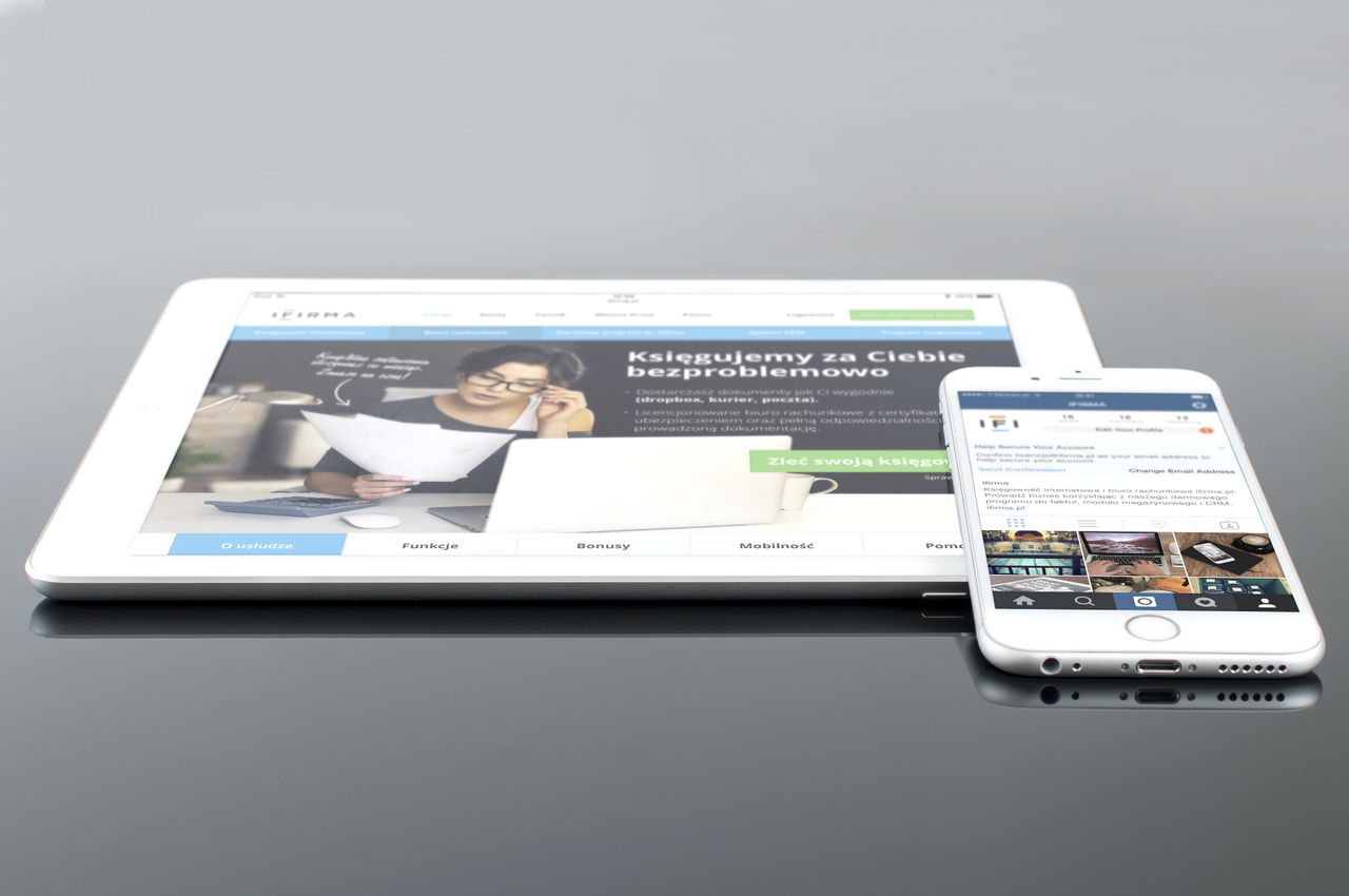 Modern tablet and smartphone showing web content on a reflective surface, emphasizing technology and connectivity.